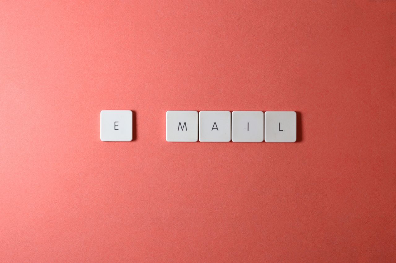 Vue en plongée d’un clavier avec des touches formant le mot email sur un fond corail.